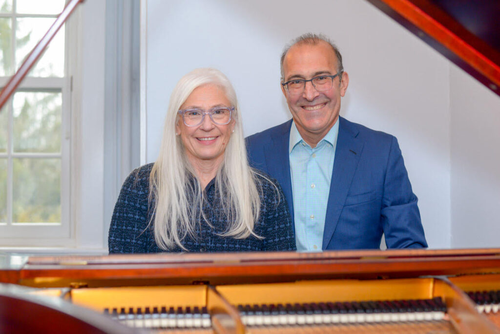 man and woman photographed through the open lid of a piano.