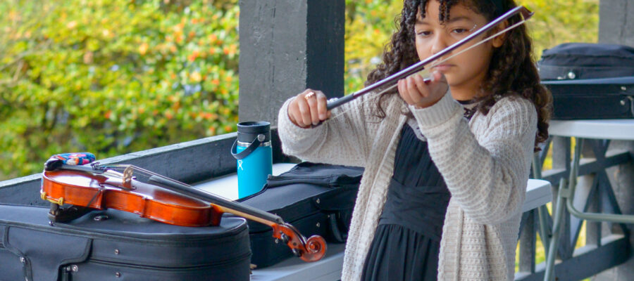 young girl putting rosin on her violin bow